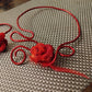 Collier artisanal rose rouge et plumes .